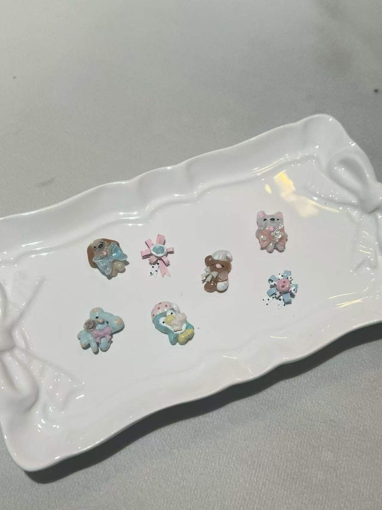 Small pastel decorative charms arranged on a white tray