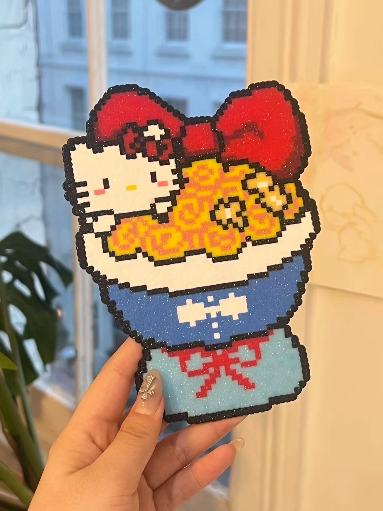 Large Hello Kitty pixel bead artwork held by a window