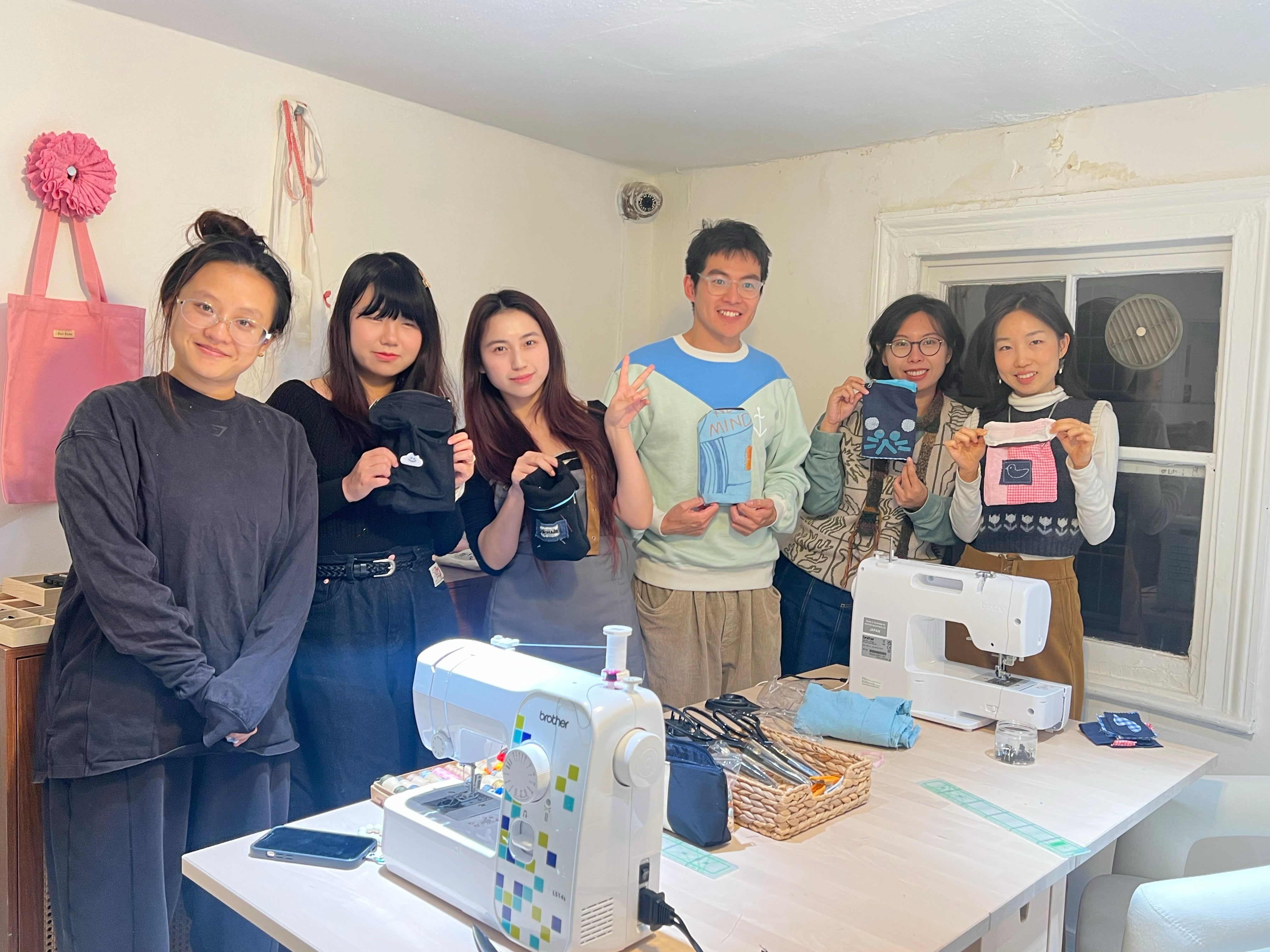 Sewing workshop participants holding finished handmade projects